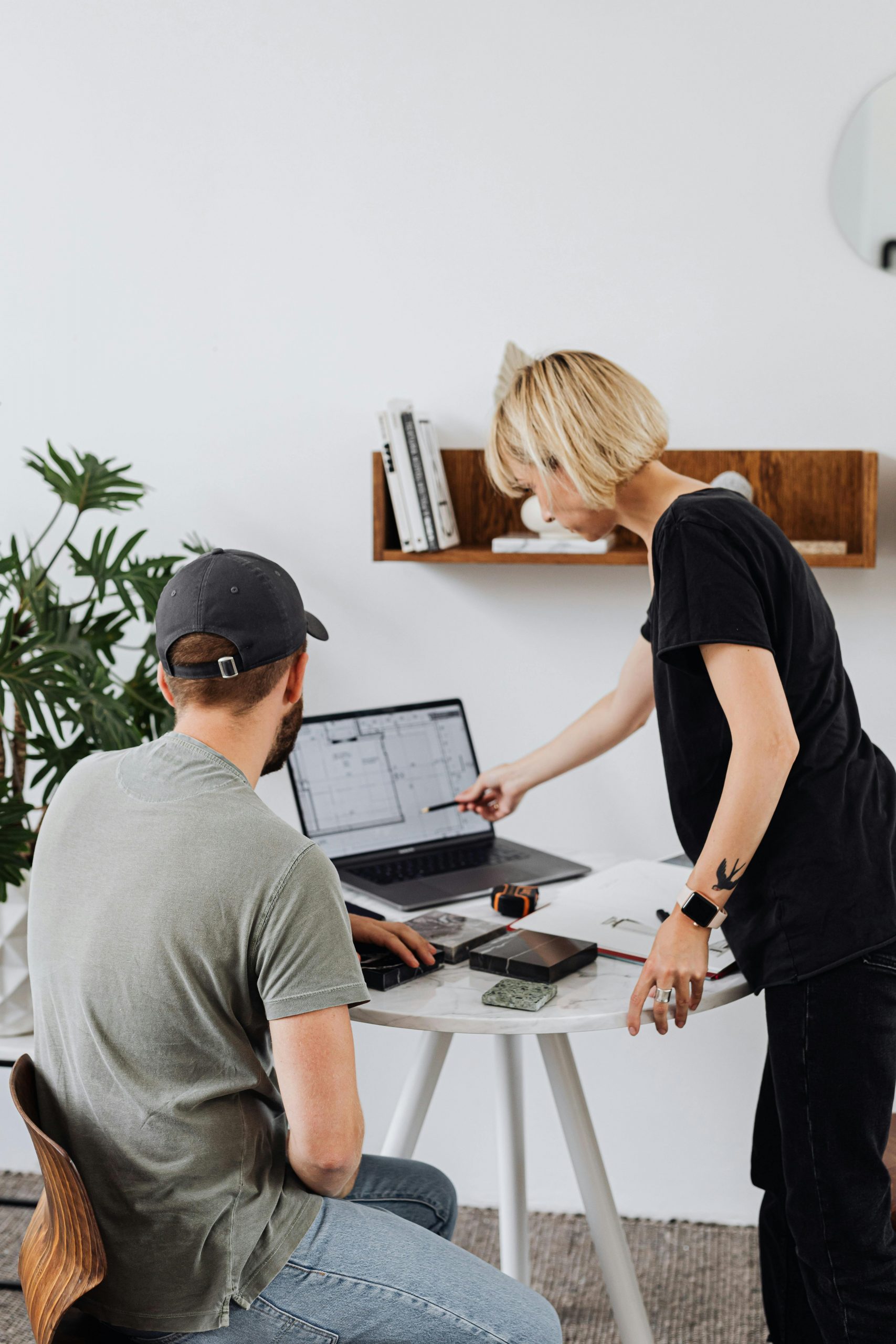 Two colleagues collaborate over a project on a laptop in a contemporary office.